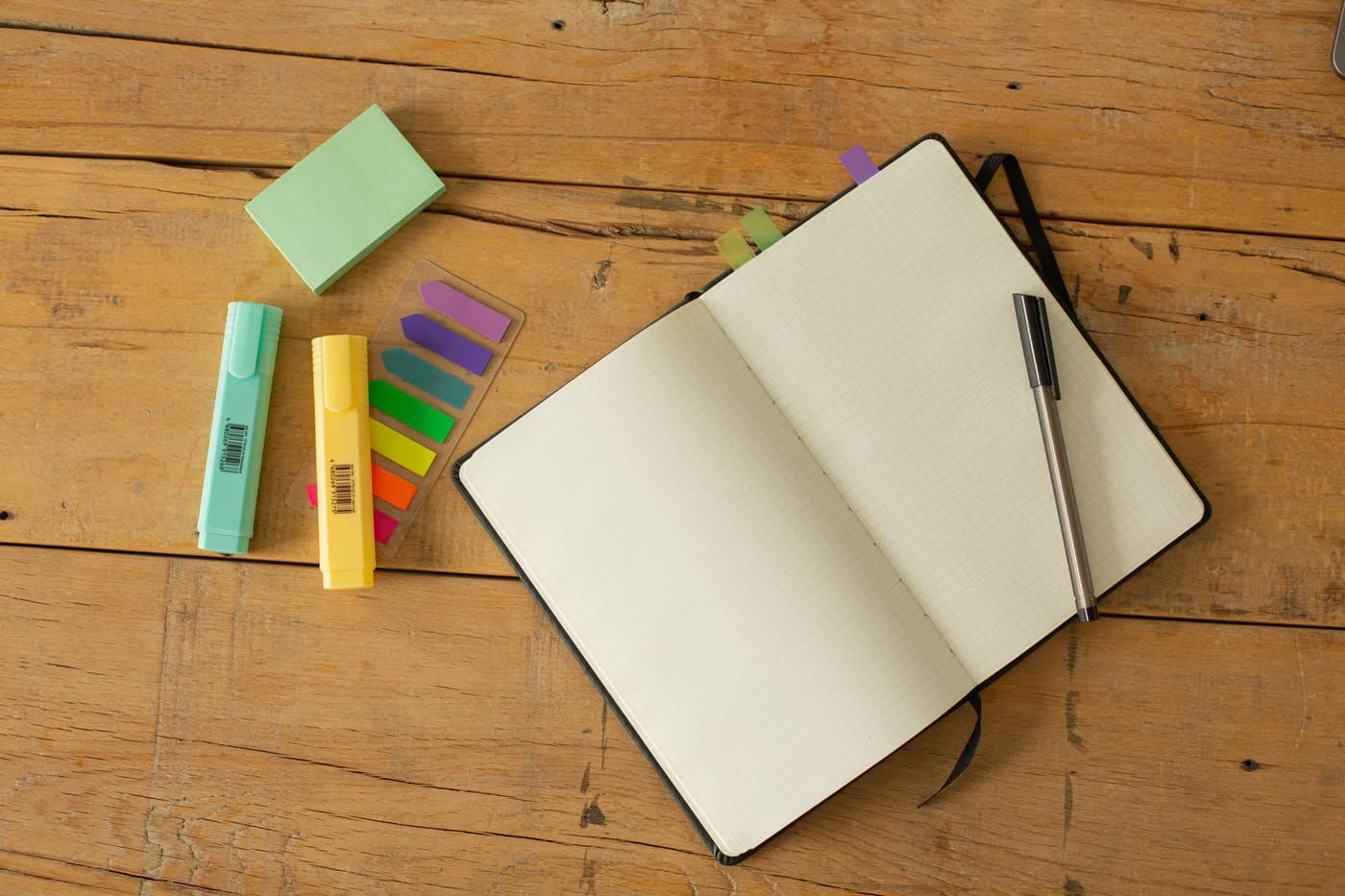 An open notebook with a pen resting on a wooden table