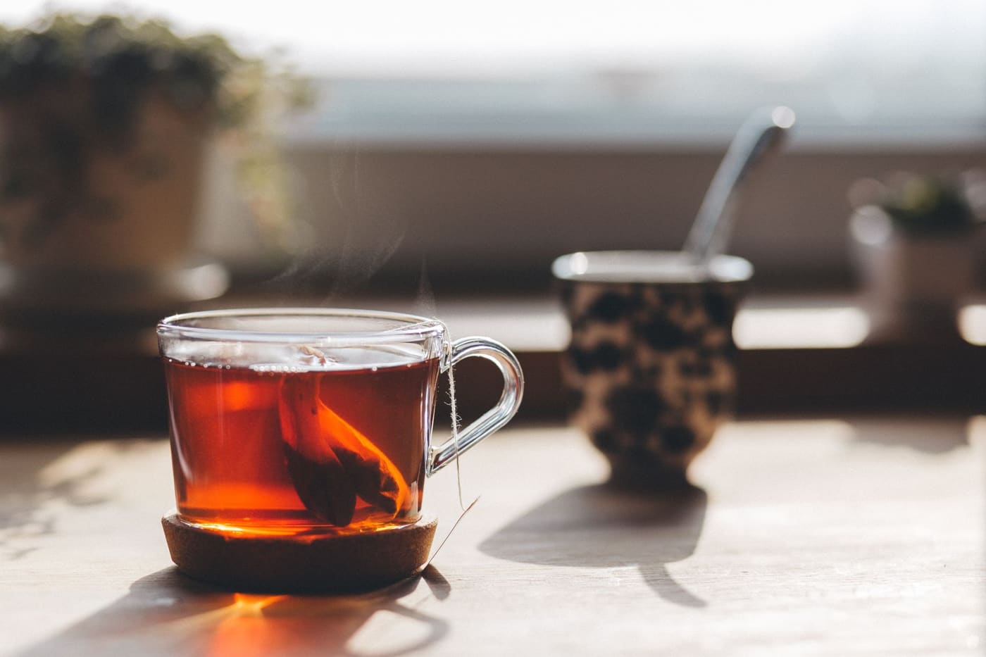A glass cup of tea steaming on a sunny windowsill
