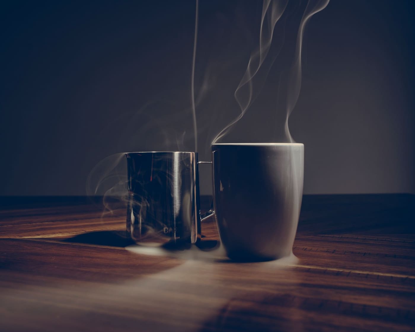Two steaming mugs side by side on a wooden table